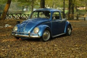 Un Volkswagen escarabajo azul aparcado en un paisaje otoñal